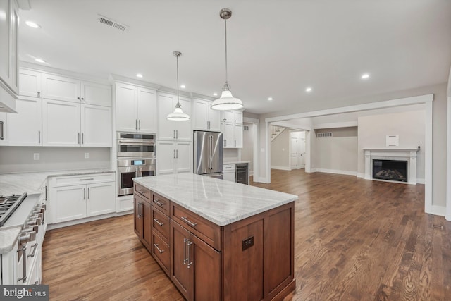 kitchen with visible vents, a fireplace, dark wood-style flooring, white cabinets, and appliances with stainless steel finishes