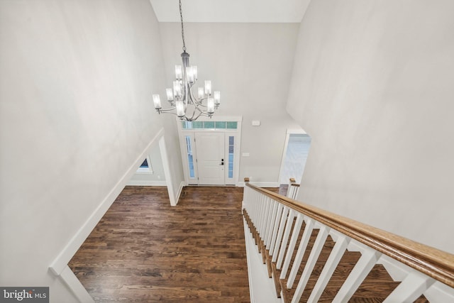 entrance foyer featuring a chandelier, baseboards, dark wood-type flooring, and a towering ceiling