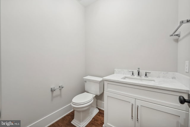 half bathroom featuring baseboards, toilet, wood finished floors, and vanity