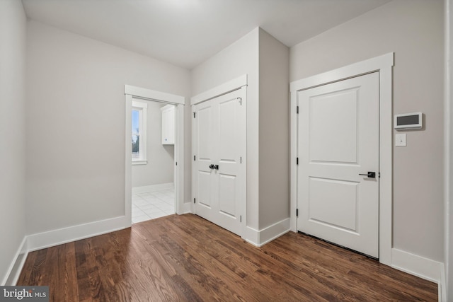 unfurnished bedroom featuring a closet, baseboards, and dark wood-type flooring