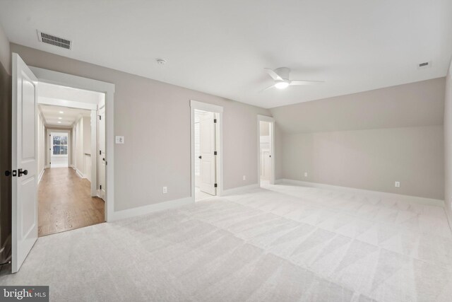 unfurnished bedroom featuring baseboards, visible vents, light carpet, and lofted ceiling