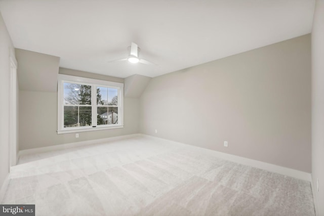 spare room with light carpet, baseboards, lofted ceiling, and a ceiling fan