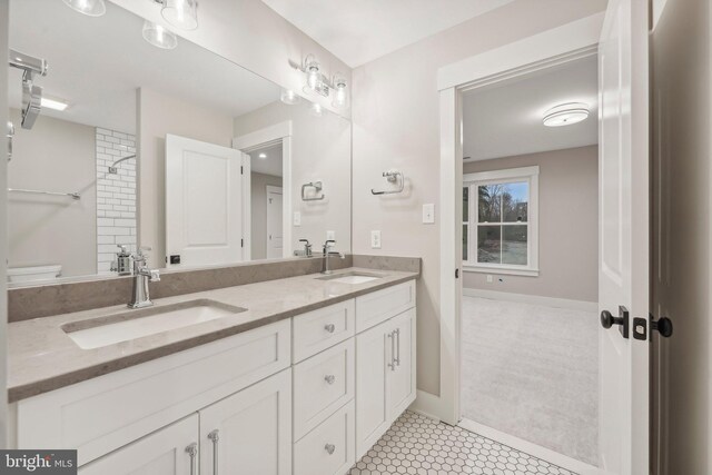 bathroom with double vanity, toilet, baseboards, and a sink