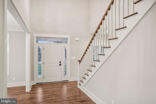 foyer featuring a towering ceiling, stairway, baseboards, and wood finished floors