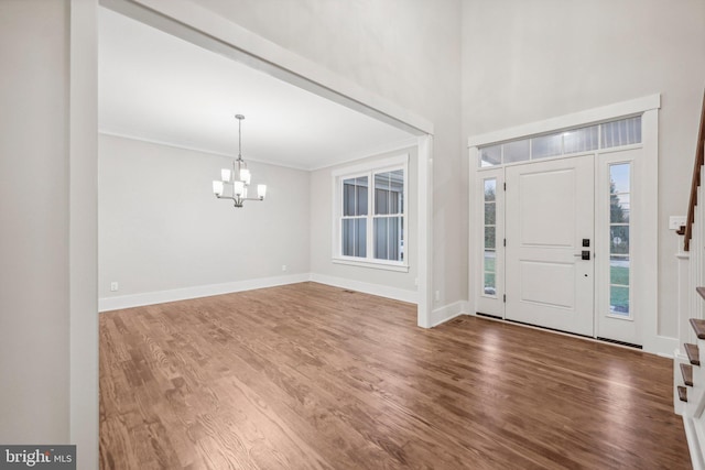 foyer entrance with wood finished floors, baseboards, a chandelier, and ornamental molding