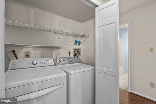 clothes washing area with laundry area, washer and clothes dryer, dark wood finished floors, and baseboards