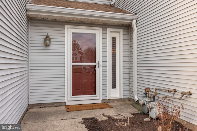 entrance to property featuring a shingled roof