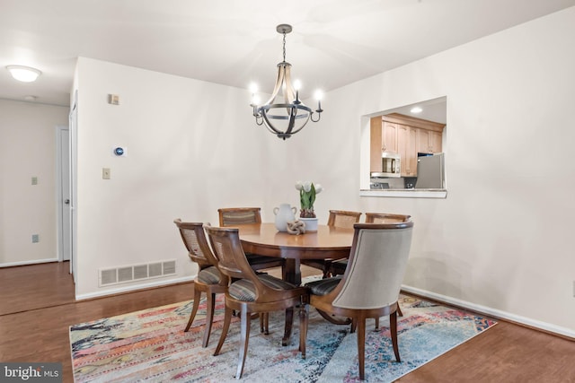 dining area with baseboards, visible vents, and wood finished floors