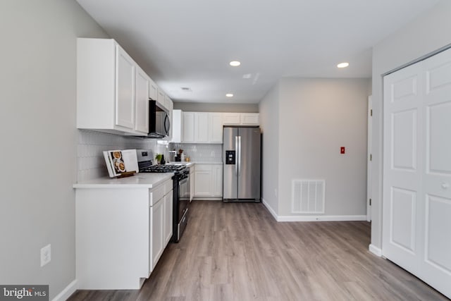 kitchen featuring visible vents, backsplash, appliances with stainless steel finishes, white cabinets, and light countertops