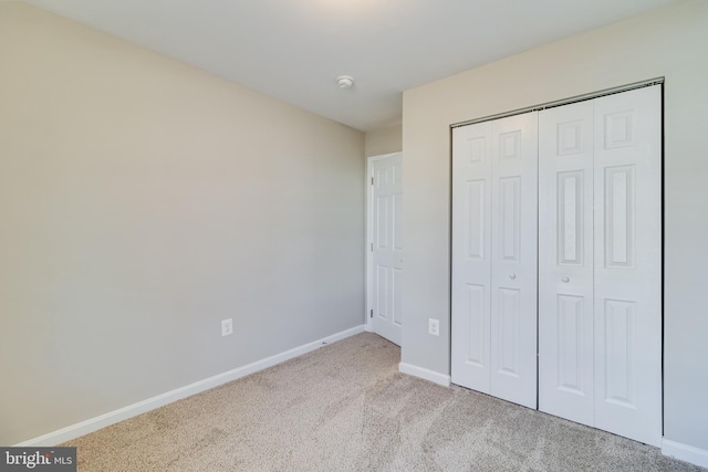 unfurnished bedroom with a closet, baseboards, and carpet flooring