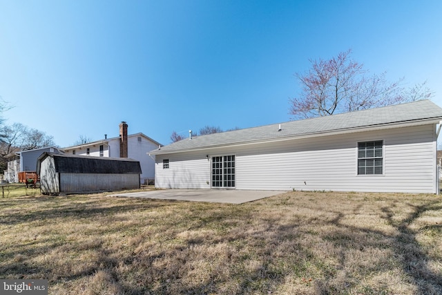 rear view of property with a yard, a shed, an outbuilding, and a patio