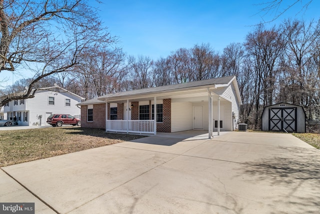 view of front of home with a storage unit, an outbuilding, covered porch, concrete driveway, and brick siding