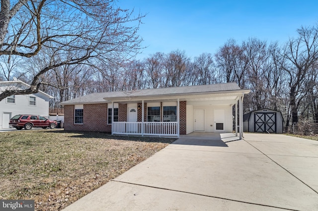 single story home featuring brick siding, concrete driveway, a front yard, covered porch, and an outbuilding