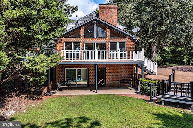 back of house featuring a patio, brick siding, stairs, a lawn, and a chimney