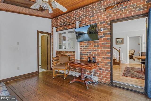 office area featuring ceiling fan, wooden ceiling, brick wall, baseboards, and hardwood / wood-style floors