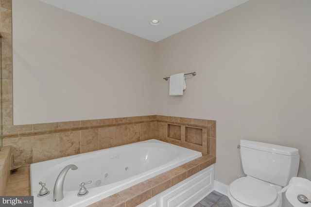 bathroom with toilet, baseboards, and a whirlpool tub