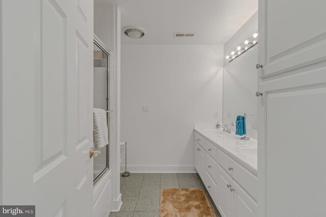 full bath featuring double vanity, visible vents, baseboards, and a sink