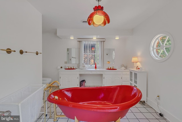 bathroom with a wealth of natural light, a freestanding tub, vanity, and tile patterned floors