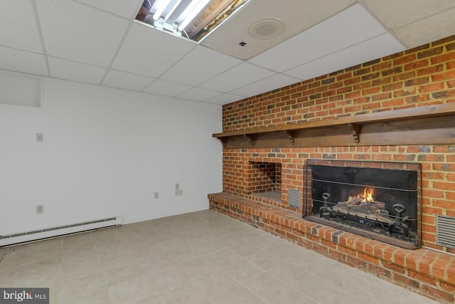 unfurnished living room featuring a drop ceiling, a fireplace, a baseboard radiator, and baseboards