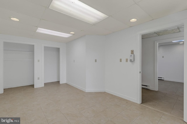 spare room featuring a baseboard radiator, a paneled ceiling, and baseboards