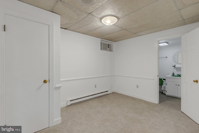 finished below grade area featuring baseboards, visible vents, baseboard heating, a paneled ceiling, and a sink