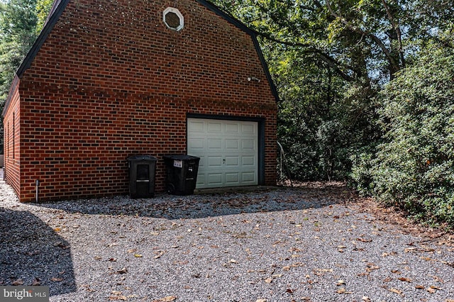 view of side of home featuring an outbuilding, gravel driveway, and brick siding