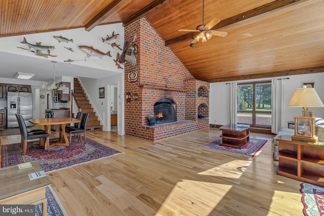 living area featuring beam ceiling, a fireplace, stairway, wood finished floors, and wooden ceiling