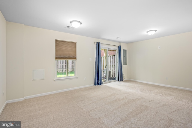 carpeted empty room featuring plenty of natural light, baseboards, electric panel, and visible vents