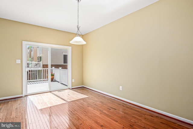 unfurnished room with baseboards and hardwood / wood-style floors