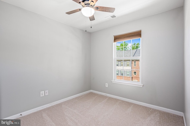 empty room featuring carpet floors, baseboards, a ceiling fan, and visible vents