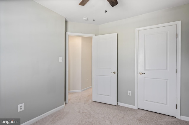 unfurnished bedroom featuring baseboards, light colored carpet, and ceiling fan