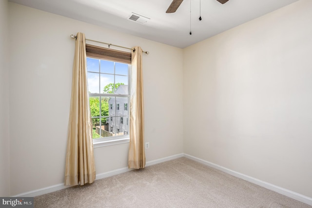 carpeted spare room with visible vents, baseboards, ceiling fan, and a wealth of natural light