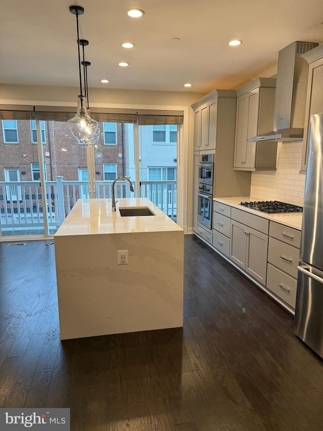 kitchen featuring a sink, gray cabinets, stainless steel appliances, wall chimney exhaust hood, and dark wood-style flooring