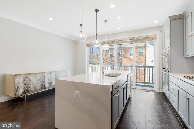 kitchen with a center island with sink, a sink, dark wood-style floors, recessed lighting, and crown molding