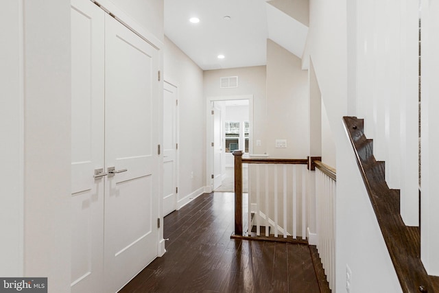 hall with recessed lighting, visible vents, an upstairs landing, and dark wood finished floors