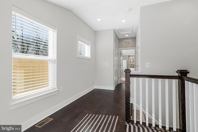 hall featuring visible vents, attic access, dark wood-type flooring, and baseboards