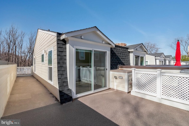 rear view of house with a patio area, a shingled roof, and fence