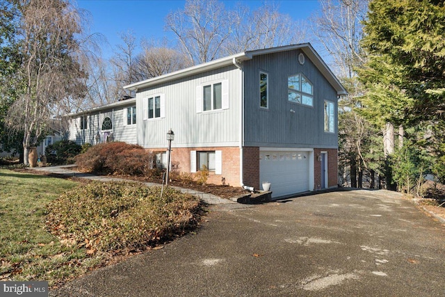 view of side of property with a garage, brick siding, and aphalt driveway