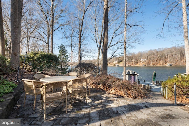 view of patio featuring a dock, outdoor dining area, and a water view