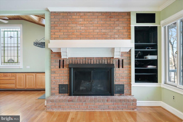 details featuring a brick fireplace, visible vents, wood finished floors, and ornamental molding