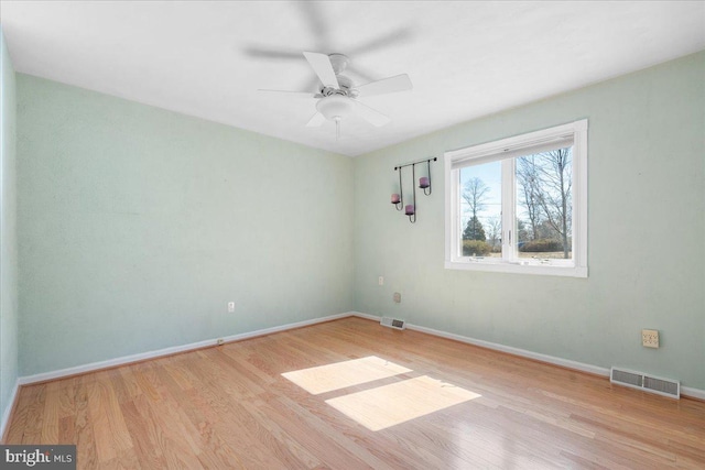 unfurnished room featuring a ceiling fan, baseboards, visible vents, and wood finished floors