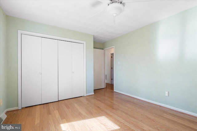 unfurnished bedroom with a closet, wood finished floors, a ceiling fan, and baseboards