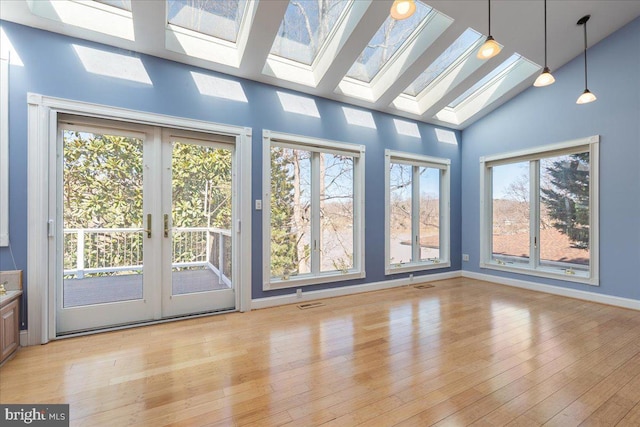 unfurnished sunroom with vaulted ceiling with skylight, visible vents, and french doors