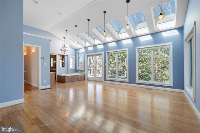 unfurnished living room featuring a skylight, baseboards, a healthy amount of sunlight, and light wood finished floors