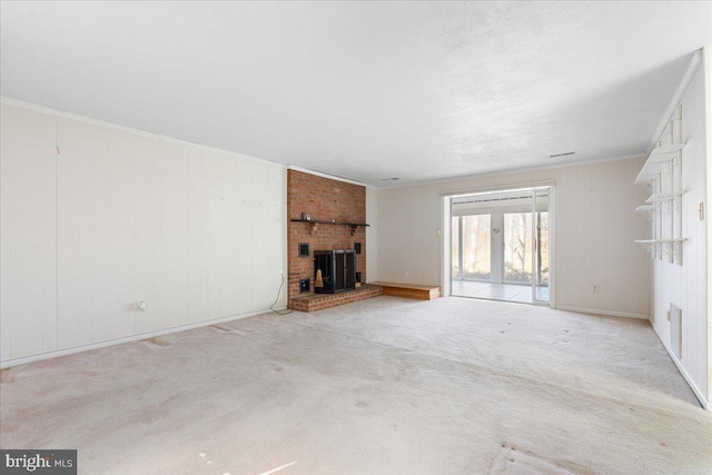 unfurnished living room with a wood stove, carpet, and ornamental molding