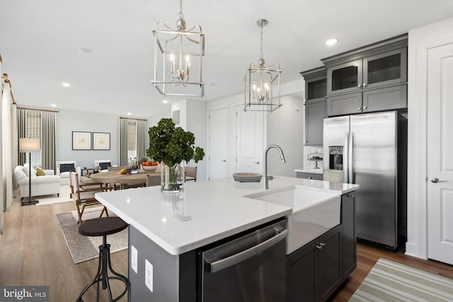 kitchen with dark wood-style flooring, light countertops, appliances with stainless steel finishes, a sink, and an island with sink