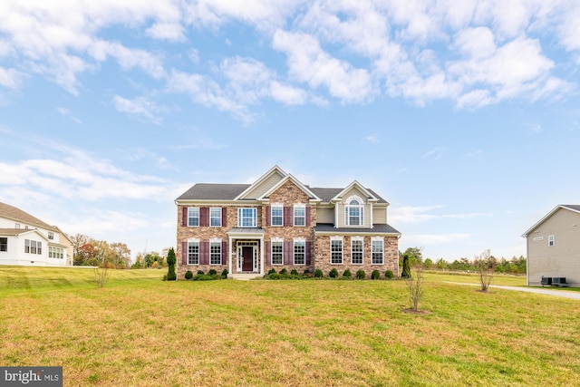 view of front of home featuring a front lawn, cooling unit, and brick siding