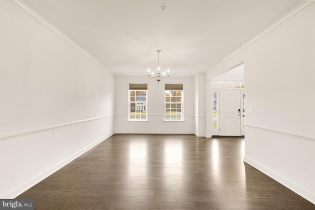 unfurnished room featuring dark wood-type flooring, a chandelier, ornamental molding, and baseboards