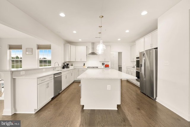 kitchen featuring stainless steel appliances, a kitchen island, a sink, wall chimney range hood, and dark wood-style floors