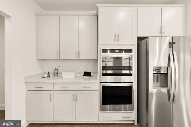 kitchen featuring stainless steel appliances, white cabinetry, and light stone countertops